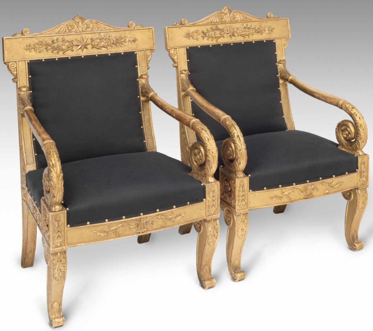 A set of four Italian walnut, carved and gilt wood and burin-finished ground (bulinato) armchairs, each with a tablet top-rail centred by a stylized foliate motif converging into an eight-point armorial star,